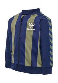 Marineblå og olivengrøn zip-up jakke med ribbet krave, der har lodrette striber, et logo på brystet og chevron-accenter på ærmerne.