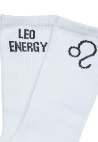 Hvite bomullssokker med ribbet tekstur som har "LEO" og "ENERGY" i svart øverst, samt et stilisert svart symbol på siden.