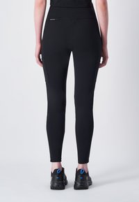 Zwarte, aansluitende legging gemaakt van rekbaar materiaal; voorzien van een zijvak en een hoge tailleband voor comfort en ondersteuning.