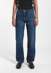 Blue denim jeans with a straight-leg fit, high waist, and five-pocket design. Features contrast stitching and a button fly closure.