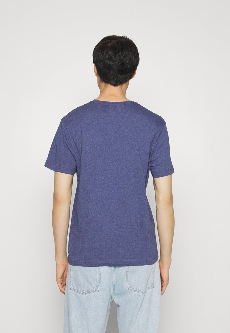 Dunkelblaues T-Shirt mit kurzen Ärmeln und Rundhalsausschnitt, aus weichem Stoff, gerader Schnitt und minimalen Nähten. Getragen mit hellblauen Jeans.