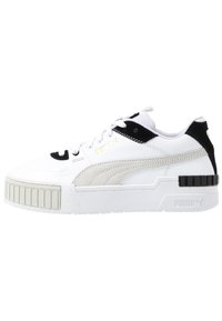 Białe sneakersy z czarnymi i szarymi akcentami, z materiałem o fakturze i grubą, teksturowaną podeszwą. Złoty detal logo z boku.