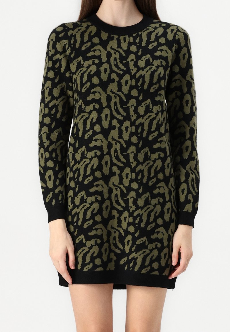 Robe noire à manches longues avec imprimé léopard abstrait vert olive, poignets ajustés, et ourlet se terminant au milieu de la cuisse sur une personne debout.