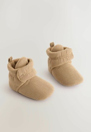 Bottines en velours côtelé beige avec un revers replié, doublure douce et accents en boucle. Design à bout rond et tissu texturé pour la chaleur.