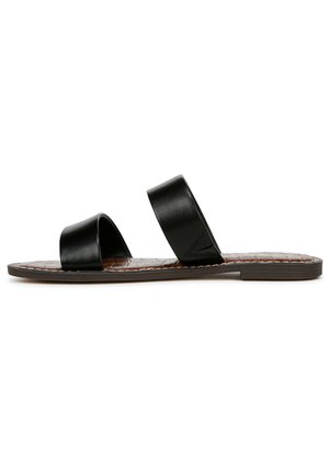 Sandale à glissière en cuir noir avec deux larges sangles, semelle plate et semelle intérieure en cuir texturé brun. Design simple sans matériel visible.