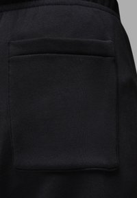 Černá tkanina s hladkou texturou, na pravé straně s pravoúhlou náprsní kapsou. Jednoduchý design bez viditelných vzorů nebo kovových prvků.