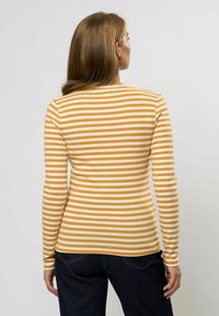 Cămașă cu mânecă lungă, cu un model în dungi galbene și albe, realizată dintr-un material ribbed. Are un guler rotund și o siluetă ajustată.