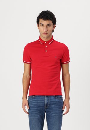 Rød polo t-shirt med slim fit, der har hvid kant på kraven og ærmerne; fem-knap lukning og lille logo på venstre bryst.
