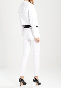 Valkoinen, lyhyt farkkutakki, musta toppi, valkoiset istuvat farkut ja mustat korkokengät. Sileä pinta, räätälöity istuvuus ja selkeät linjat.