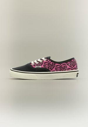 Χαμηλής κοψιάς παπούτσι Vans με μαύρη μύτη, λευκά κορδόνια και ροζ ύφασμα διακοσμημένο με μοτίβα γκράφιτι σε σχήμα μαύρης καρδιάς.