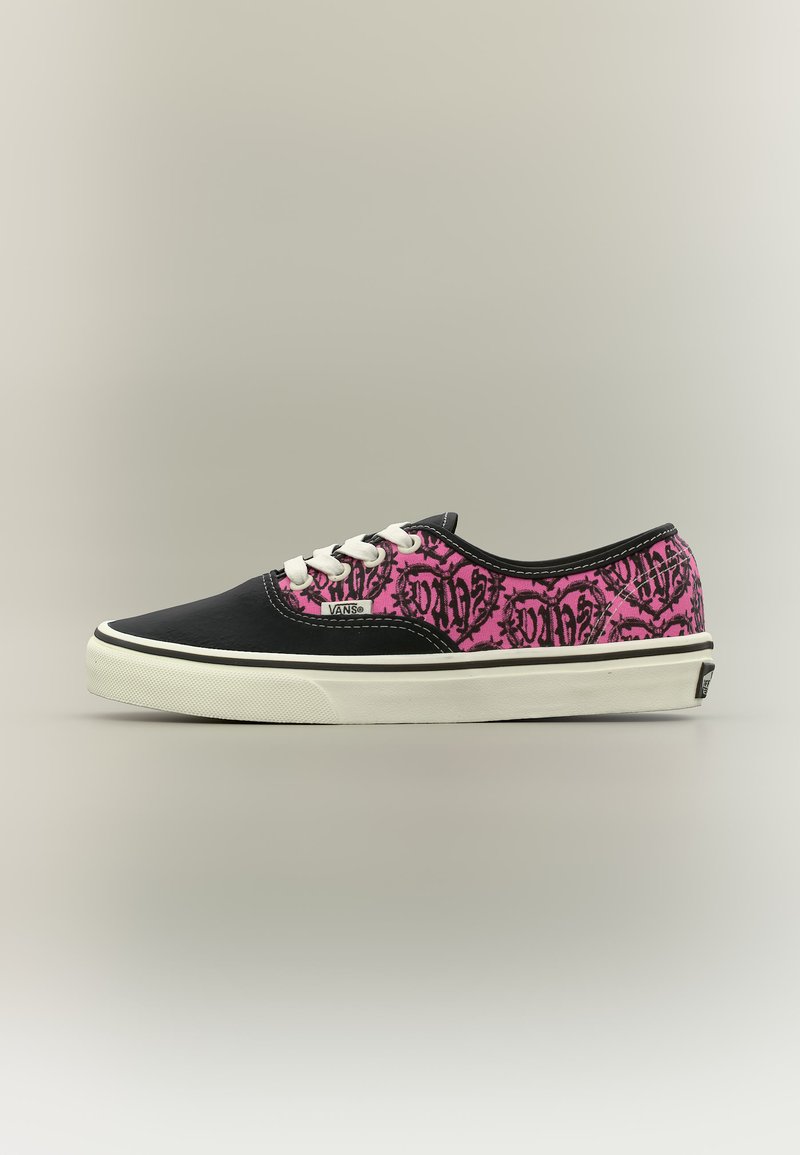 Χαμηλής κοψιάς παπούτσι Vans με μαύρη μύτη, λευκά κορδόνια και ροζ ύφασμα διακοσμημένο με μοτίβα γκράφιτι σε σχήμα μαύρης καρδιάς.