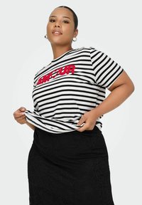 Camiseta de rayas blancas y negras con texto bordado en rojo que dice "AMOUR". Combinada con una falda negra texturizada. Ajuste casual, mangas cortas.