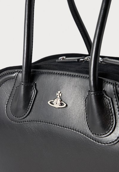 Μαύρη δερμάτινη τσάντα με ραμμένες λαβές και ασημένιο λογότυπο σφαίρας στο κέντρο του μπροστινού πάνελ πάνω σε απλό φόντο.