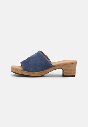 Blå ruskind åben tå mule sandal med træplatformsål og blokhæl på hvid baggrund.