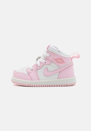 Lille Air Jordan sneaker i hvid og pink med snørebånd, Nike swoosh og vinget basketball-logo i siden.