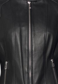 Czarna skórzana kurtka z centralnym srebrnym zamkiem błyskawicznym i dwiema bocznymi kieszeniami na zamek, z widocznymi szczegółowymi szwami i gładką fakturą.