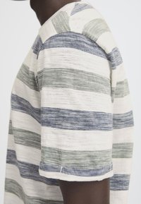 Randig t-shirt med horisontella linjer i marinblå, grön och krämfärgad; mjuk textur; rund halsringning; korta ärmar med sydda cuffs.