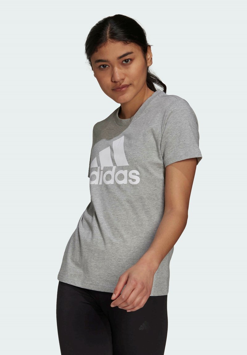 Szara bawełniana koszulka z krótkim rękawem z dużym białym logo Adidas. Regularny krój. Połączona z czarnymi legginsami.
