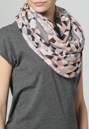 Femme portant un t-shirt gris à manches courtes et une écharpe infinie à motifs géométriques multicolores autour du cou.