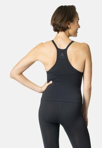 Zwarte geribde sportieve tanktop met een racerback ontwerp, subtiel logo op de achterkant en zachte, gestructureerde stof. Aansluitende silhouet.