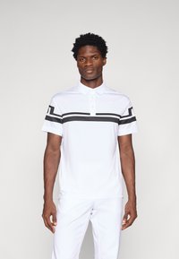 Camisa polo branca com detalhes em preto, mangas curtas e gola. Tecido suave, design ajustado, apresentando um logótipo no peito.