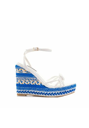 Sandalia de cuña con material trenzado en azul y blanco, correa en el tobillo blanca y un diseño de plataforma texturizada y multicolor.