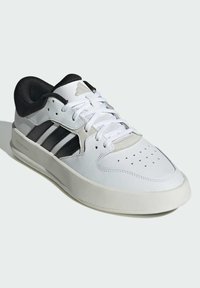 Sneaker bianco con accenti neri e grigi, caratterizzato da tre strisce nere sul lato, punta perforata e colletto imbottito nero per il comfort.