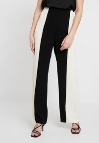 Höga vida byxor med en svart och vit färgblockdesign, slätt tyg och skräddarsydd passform. Accenterade med minimal hårdvara.