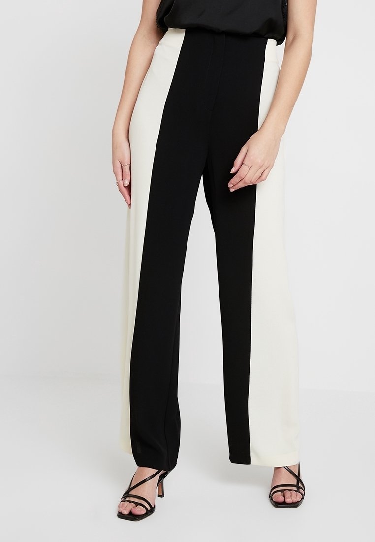 Höga vida byxor med en svart och vit färgblockdesign, slätt tyg och skräddarsydd passform. Accenterade med minimal hårdvara.