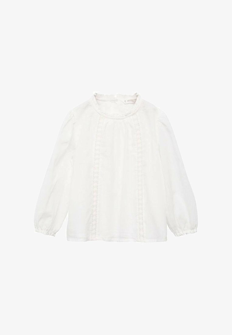 Blusa bianca a maniche lunghe con scollo rotondo, caratterizzata da dettagli in pizzo lungo la parte anteriore e polsini arricciati. Realizzata in tessuto leggero.