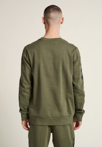 Olijfgroen sweatshirt van katoenmix, met lange mouwen en zwarte chevronaccenten, ribgebreide manchetten en zoom. Casual fit met ronde hals.
