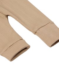Beige, ribbelige Langarmshirts mit umgeschlagenen Bündchen, hergestellt aus einem strukturierten Stoff, der eine glatte, gleichmäßige Oberfläche und einen dezenten Glanz aufweist.