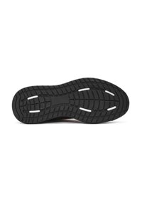Semelle de chaussure en caoutchouc noir avec un motif de traction texturé, présentant des accents blancs et des rainures pour l'adhérence. Forme plate et arrondie.