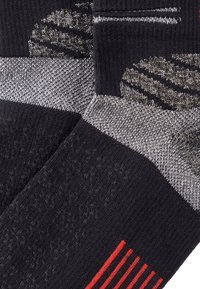 Calzini a righe nero e grigio con superfici texture, un accento a strisce rosse e diversi design di maglia per una maggiore aderenza e stile.