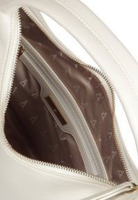 Biała skórzana torebka na zamek. Wnętrze wykończone beżową podszewką z delikatnym wzorem serc oraz małym logo.