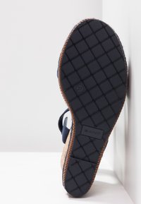 Sandale bleu marine avec une semelle extérieure en caoutchouc noir texturé. Comprend une semelle intermédiaire en liège et des brides réglables. Taille 37 indiquée sur la semelle.