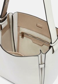 Biała skórzana torba typu tote z beżowym wnętrzem, wyposażona w wewnętrzną kieszeń na zamek błyskawiczny i gładką fakturę. Krawędzie mają subtelne czarne akcenty.