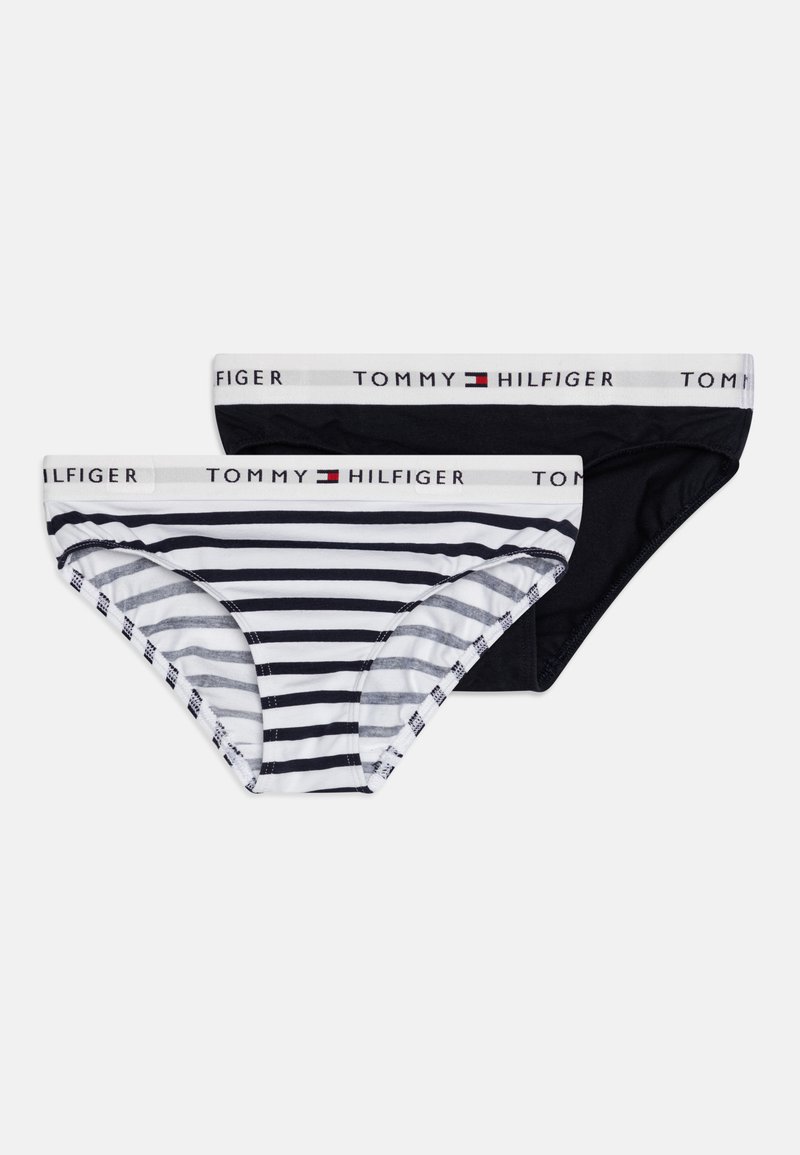 Deux paires de sous-vêtements pour femmes : une noire et une rayée en blanc et marine. Les deux possèdent une taille avec le logo "Tommy Hilfiger".