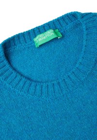 Tyrkysový pletený svetr s žebrovaným kulatým výstřihem. Obsahuje zelenou etiketu s nápisem "UNITED COLORS OF BENETTON." Měkká textura.