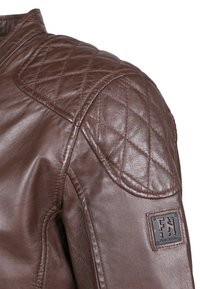 Brun läderjacka med quiltad axelp padding och en texturerad yta. Innehåller ett broderat logomärke på ärmen.