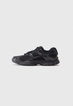 Czarny sportowy sneaker z siateczkową i syntetyczną nakładką, z przodu na sznurówki i amortyzowaną podeszwą, pokazany z profilu na jednolitym tle.