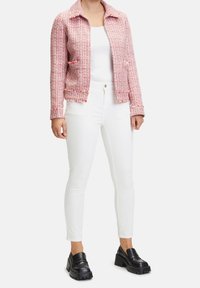 Różowa i biała marynarka z tweedu z kołnierzykiem, dwiema przednimi kieszeniami i teksturowaną tkaniną, w połączeniu z białymi obcisłymi dżinsami i czarnymi mokasynami.