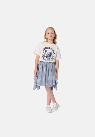 Witte T-shirt met blauwe "KENZO PARIS" opdruk, gecombineerd met een lichtblauwe, met patroon verseierde rok en witte instapschoenen.