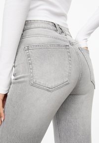 Grå denim jeans med en tætsiddende pasform, der har høj talje, to baglommer og subtil tekstur. Materialet er let falmet.