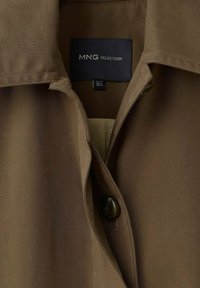 Camicia in tessuto intrecciato marrone con colletto, chiusura con un bottone e etichetta MNG Selection visibile all'interno del collo.