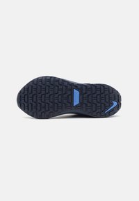 Niebieska podeszwa sportowego buta z teksturowanej gumy, z wyraźnym logo Nike i wzorzystym bieżnikiem zapewniającym przyczepność.