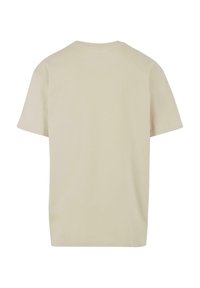 Šviesiai beige spalvos medvilnės marškinėliai. Su apykakle, trumpomis rankovėmis ir laisvu pritaikymu. Nėra matomų logotipų ar raštų.