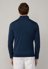 Marinefarbener Pullover mit langen Ärmeln und strukturiertem Strick. Gerippter Saum und Kragen, mit einem karierten Muster an den Bündchen. Rückansicht.