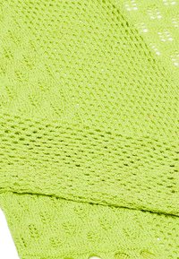 Țesătură tricotată verde deschis, cu un model de lucru deschis, având un finisaj texturat și un model de cusături variate, inclusiv secțiuni simple și decorative.