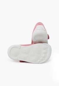 Pink fabric shoes with a white rubber sole. The sole features textured patterns and small logo detailing. Soft upper design for comfort.